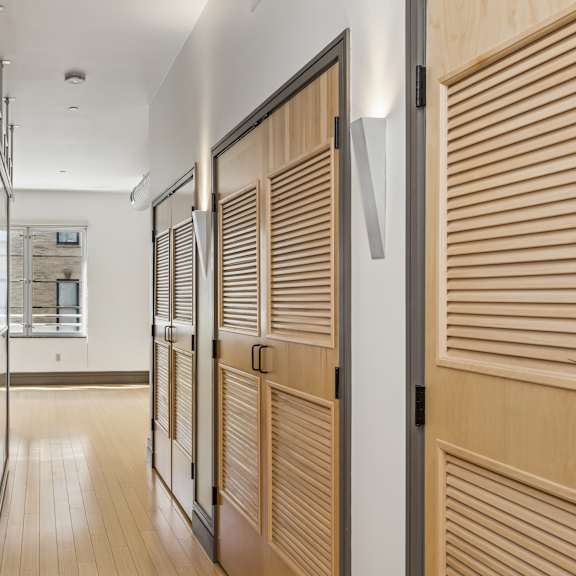 a hallway with wooden doors and a white wall.