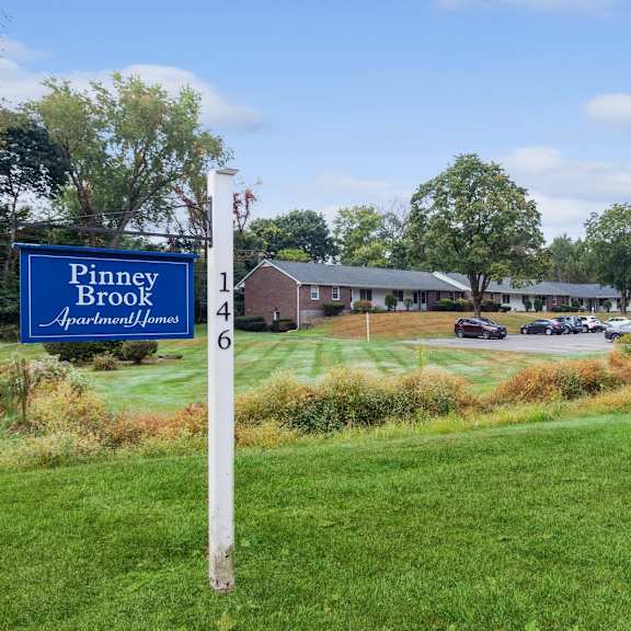 a blue and white sign in the grass in front of a building