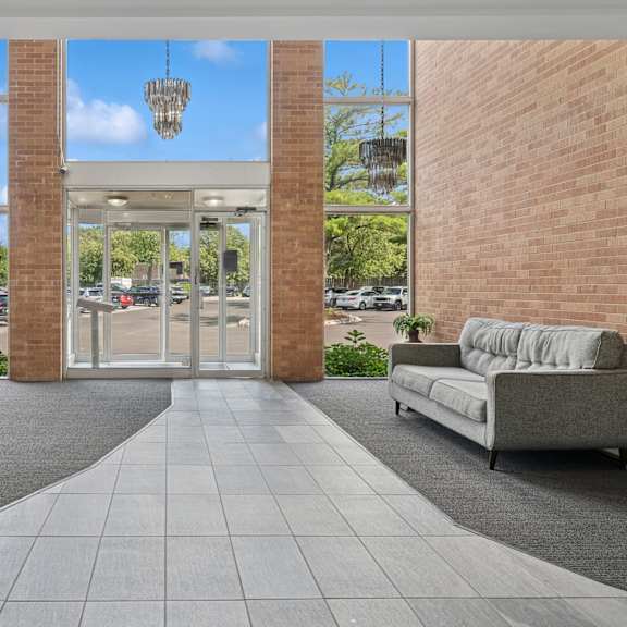 a modern building entrance with a glass door and a grey sofa.