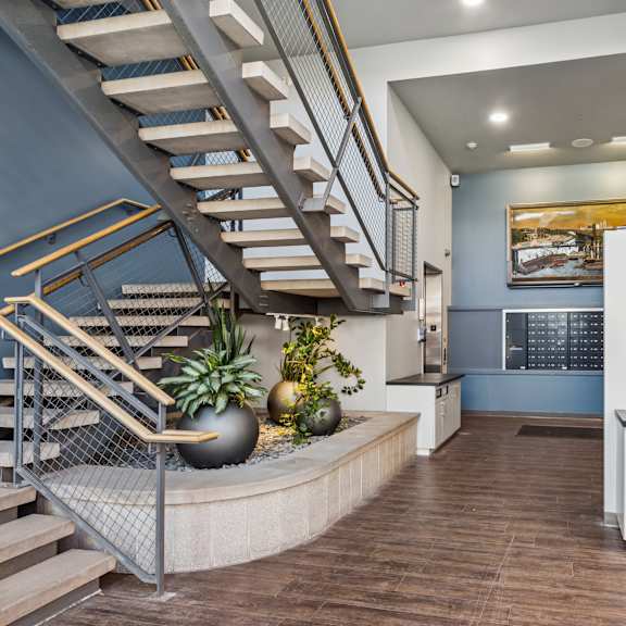a staircase with a metal railing and wooden steps leads to a brightly lit room with a kitchen area.