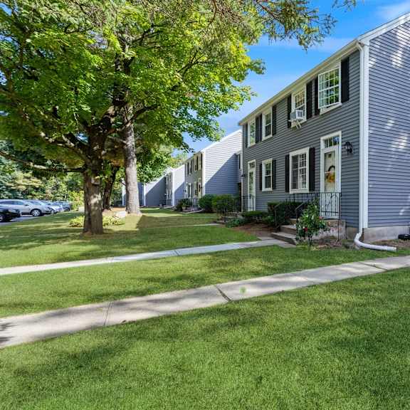 exterior view of our apartments with a sidewalk and landscaping in front at arbor commons