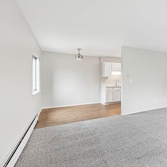 living room with a grey carpet and white walls and kitchen on the far end