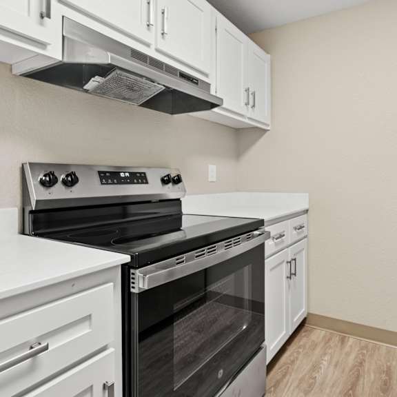 a kitchen with white cabinets and a black refrigerator.