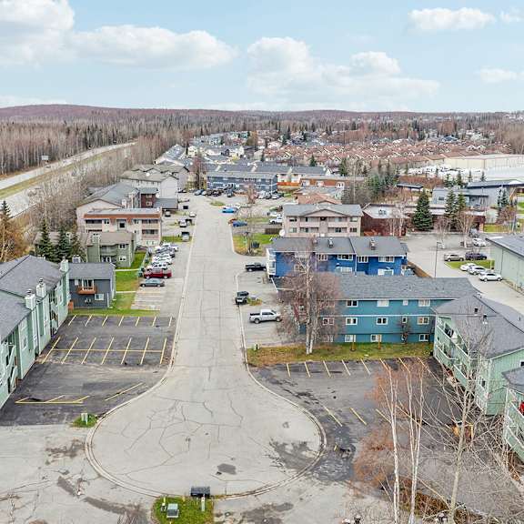 a parking lot is surrounded by buildings and trees.