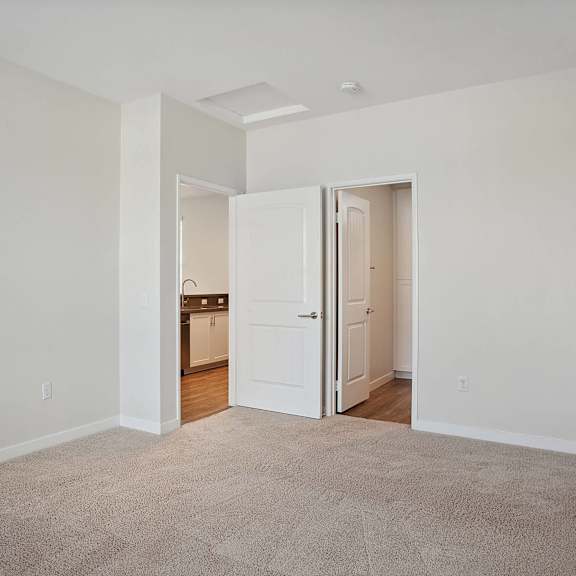a bedroom with two doors and a carpeted floor at arrive at rancho belago, moreno valley