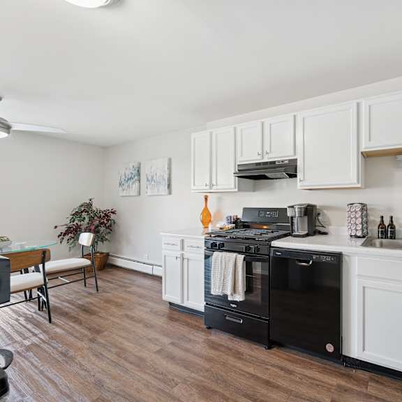 a kitchen with white cabinets and a black dishwasher.