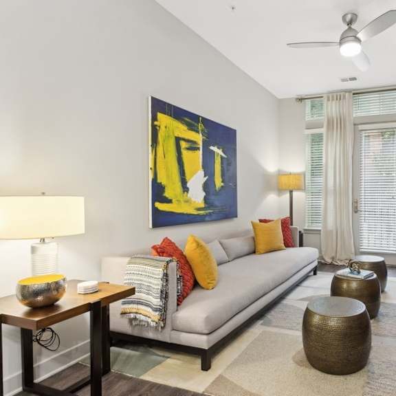 a living room with a gray couch and a yellow painting