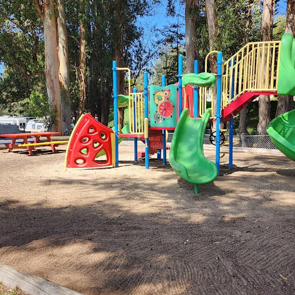 a playground with a green slide and a red and yellow climbing structure at salinas sunset apartments, salinas, ca