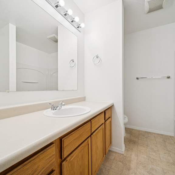 a white bathroom with a sink, mirror, and bathtub.