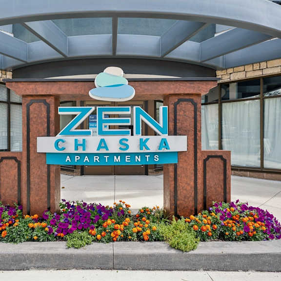 a zen chaska apartments sign is in front of a building.