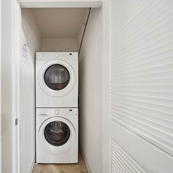 a white washing machine and dryer in a small, white-walled laundry room.