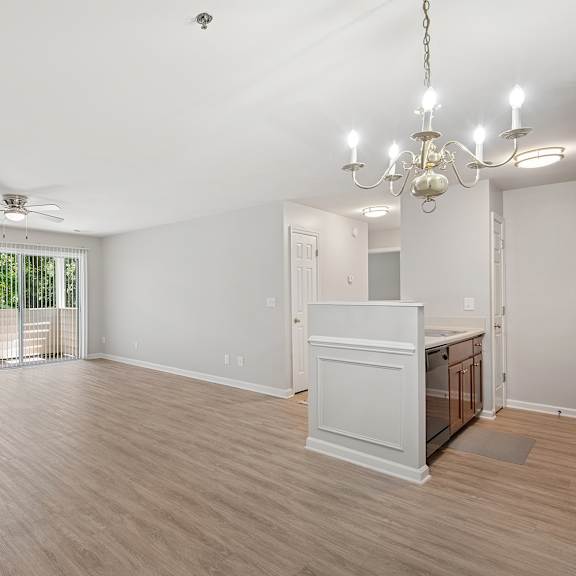 a room with a wooden floor, a ceiling fan, and a chandelier.