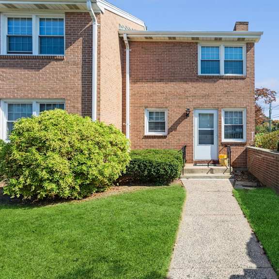 the front of a brick house with a sidewalk and grass