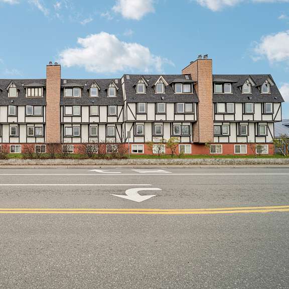 a large building with a white and black facade sits next to a road with a white arrow painted on it.