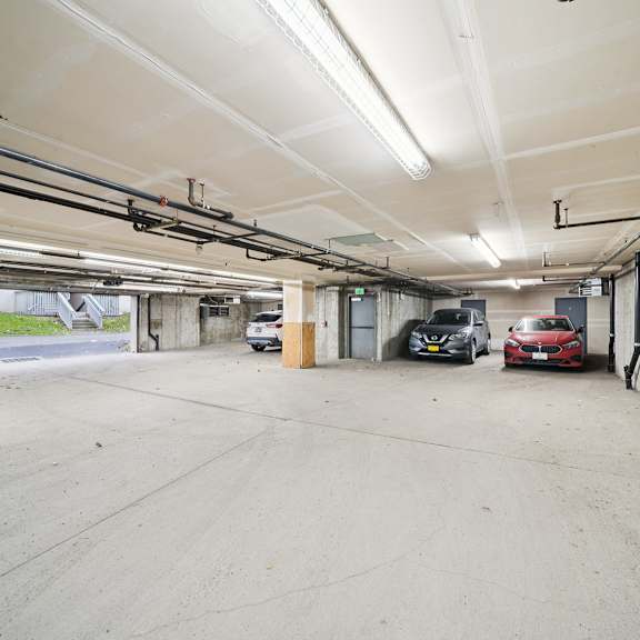 a large, empty parking garage with a red car parked in the distance.