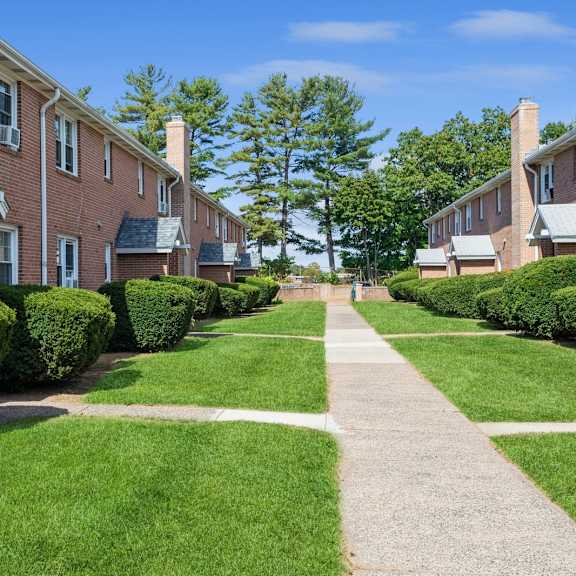 a sidewalk in front of a row of brick apartment building