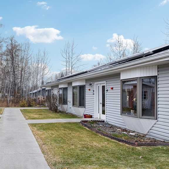 a row of houses with a sidewalk in between.