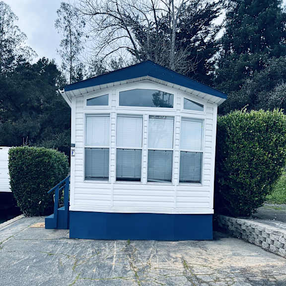 a small white and blue building with a number 109 painted on the ground in front of it.