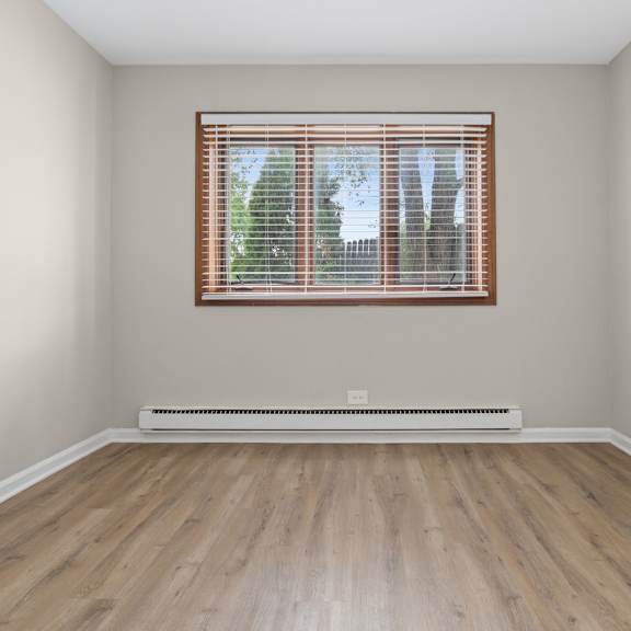 a room with a window and a radiator on a wooden floor.