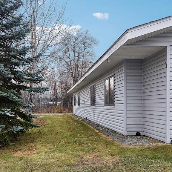 a house with a grey siding and a tree in front of it.