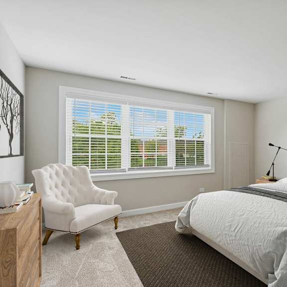 a bedroom with a large bed, a chair, and a window with blinds.