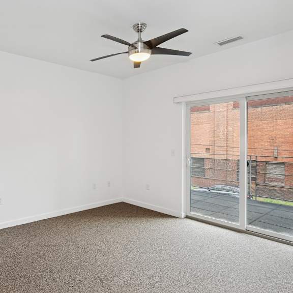 a room with a ceiling fan and a sliding glass door.