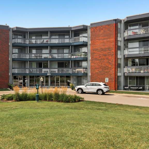 a large apartment complex with a grassy courtyard in front.