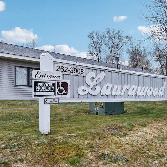 a sign for laurawood farms stands in front of a building.