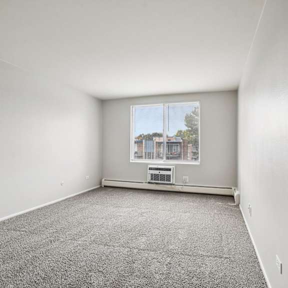 a room with a carpeted floor and a window showing a view of a building outside.