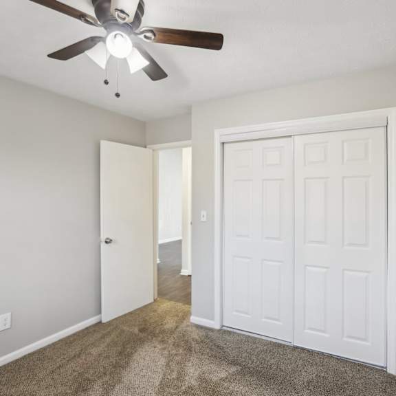 a room with a ceiling fan and a white door.