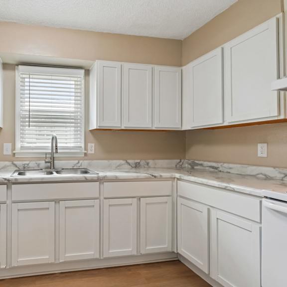 a kitchen with white cabinets and a marble countertop.