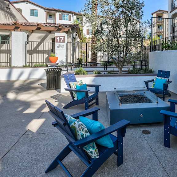 a patio with blue chairs and a table with a tray of fruit on it.