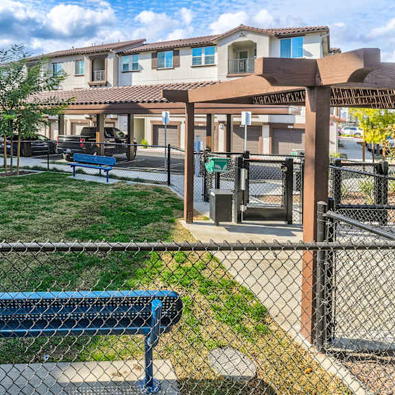 a blue bench sits in front of a fence in a grassy area.