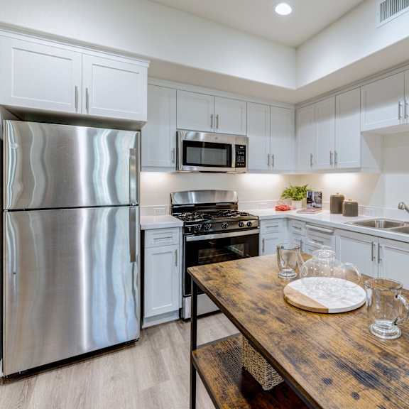 a kitchen with a wooden table and stainless steel appliances.