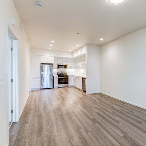 a spacious room with wooden flooring and white walls.