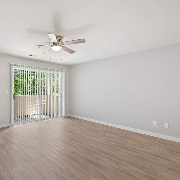 a room with a ceiling fan and sliding glass doors.