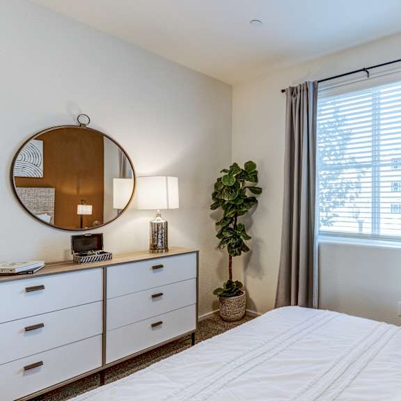 a bedroom with a large bed, a mirror, and a potted plant.