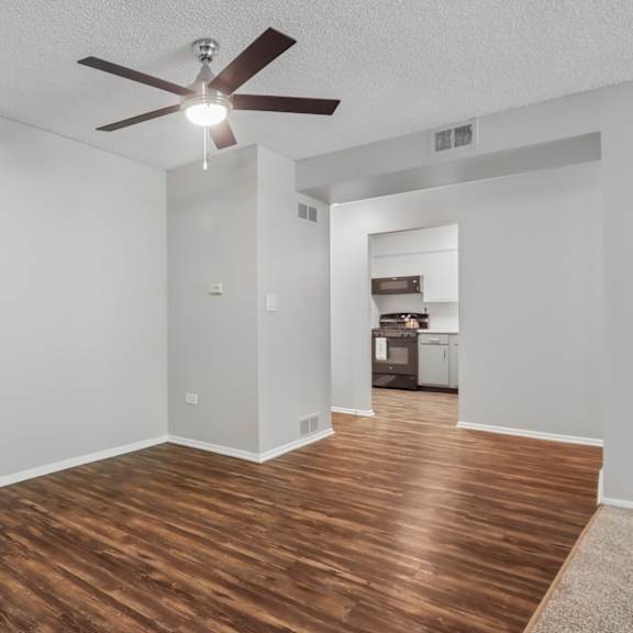 a room with a ceiling fan and wooden flooring.