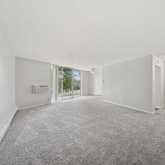 a spacious room with grey carpeting and white walls.
