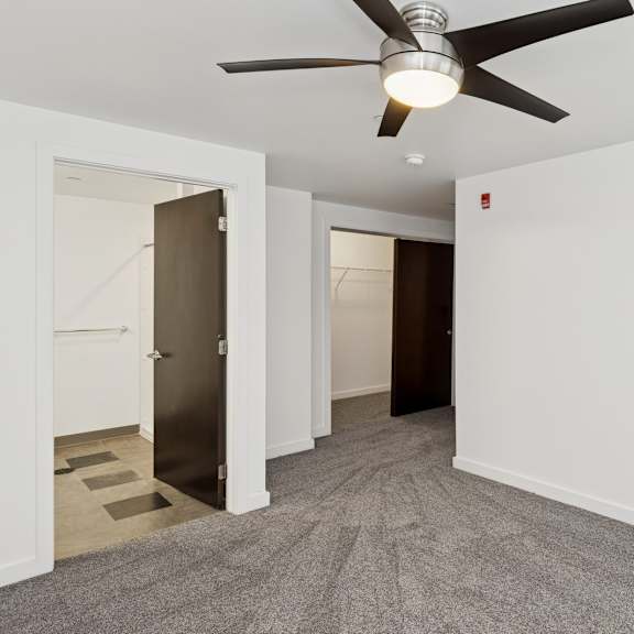 a room with a ceiling fan and carpeted floor.