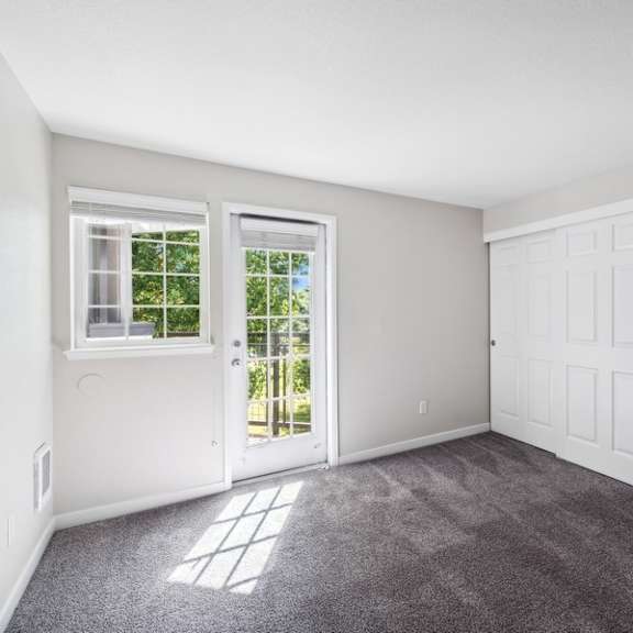 an empty living room with white walls and doors and carpet at sundial apartments, wilsonvile, oregon