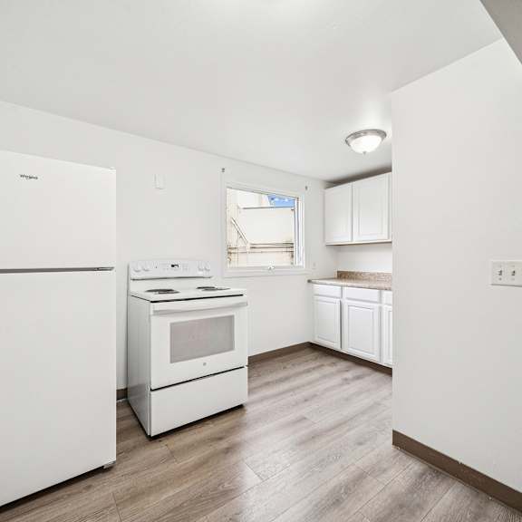 a white kitchen with a refrigerator, oven, and microwave.