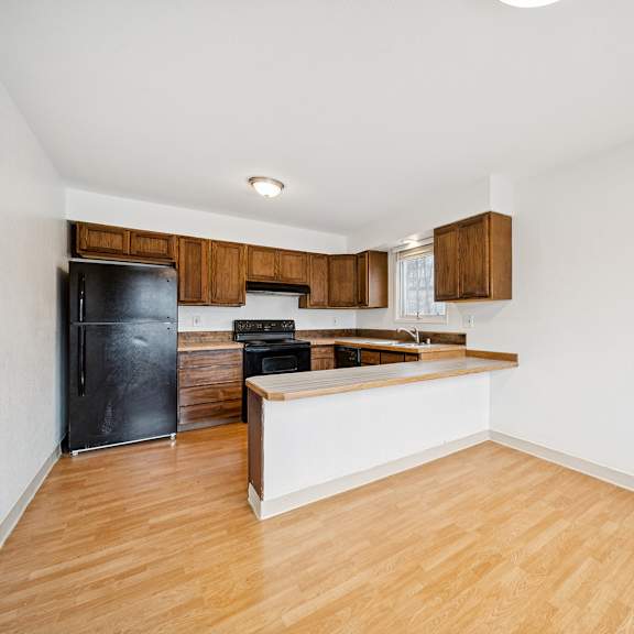 a kitchen with a black fridge and wooden cabinets.