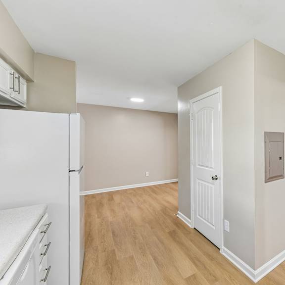 a kitchen with a white refrigerator and wooden floors.