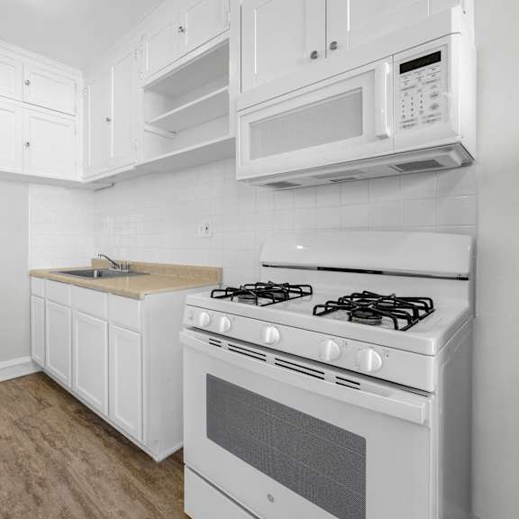 a white kitchen with a stove, microwave, and cabinets at pleasant oak apartments, oak park, illinois