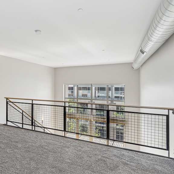 a room with a grey carpet and a black railing.