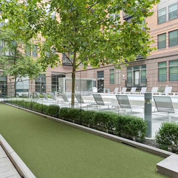 a courtyard with grass and chairs in front of a building