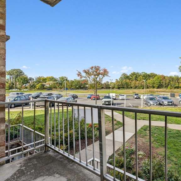 the view of the parking lot from the balcony of a building with a metal railing at briarwood apartments, dumfries