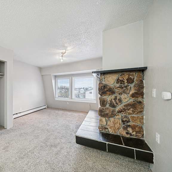 a room with a stone fireplace and a built-in shelf.