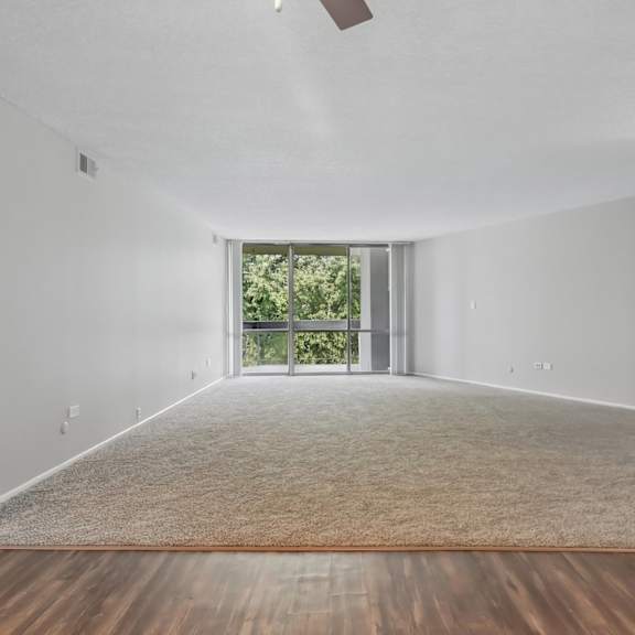 a spacious room with a carpeted floor and a ceiling fan.